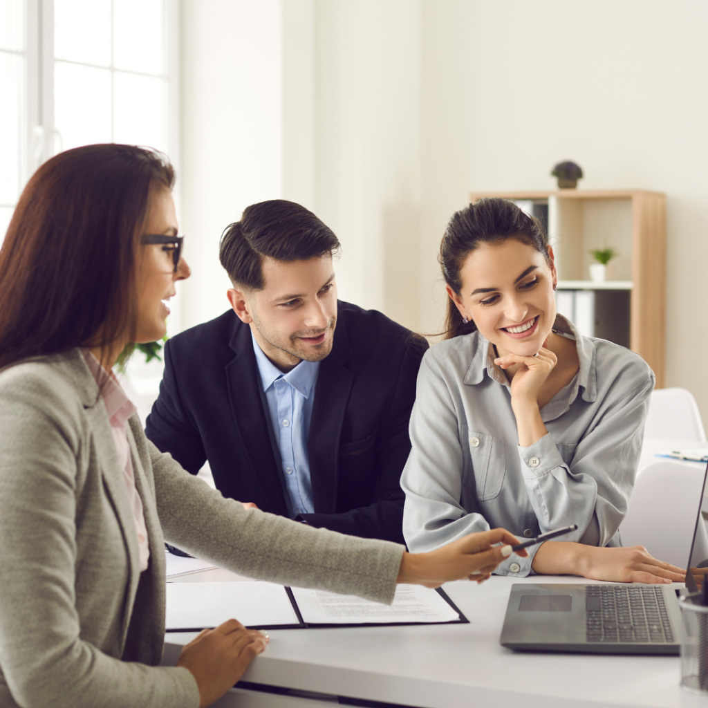 A picture of first-time homebuyers sitting with a mortgage loan officer applying for a home loan.